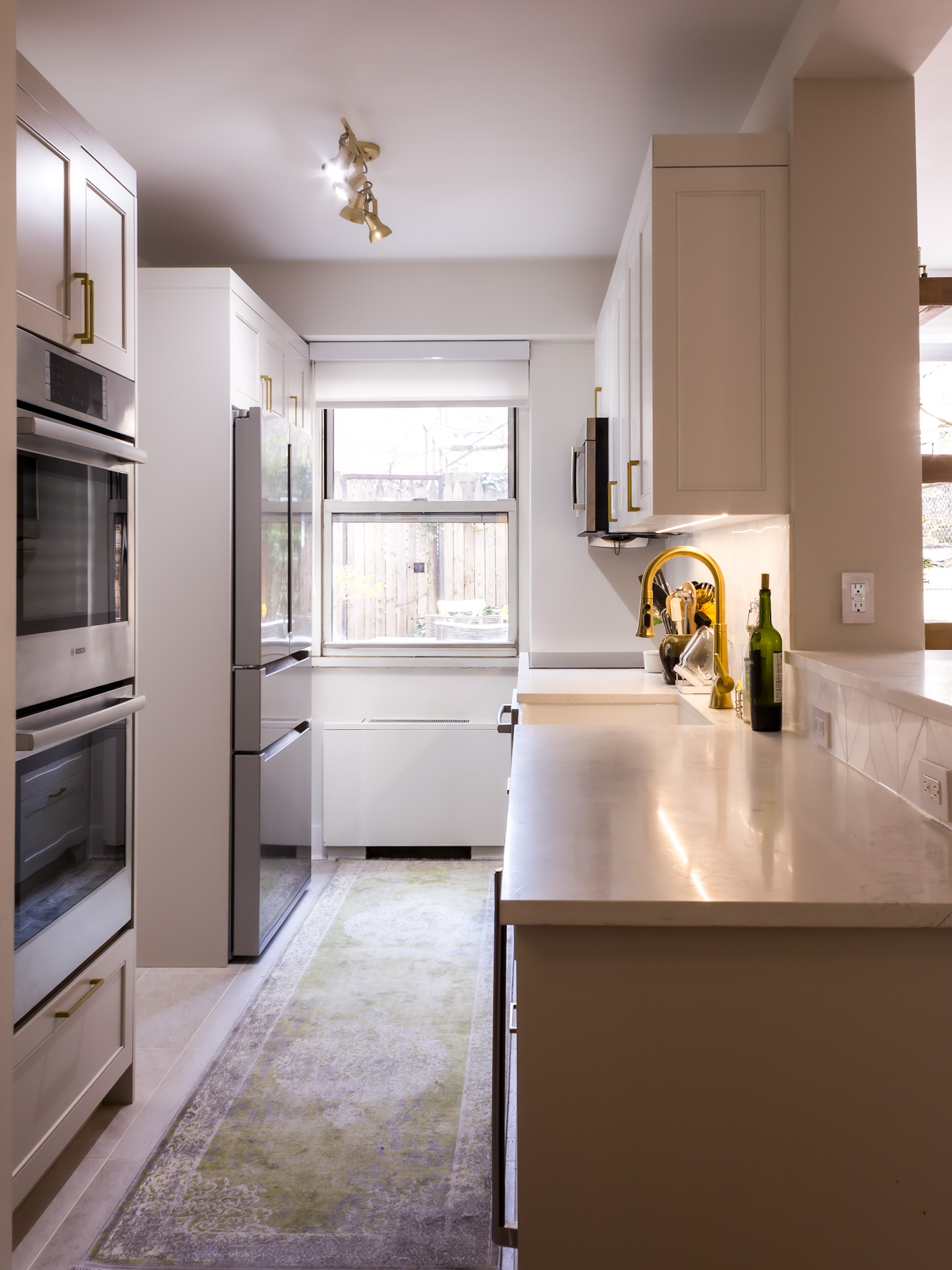Galley kitchen — warm greige shaker cabinetry with brushed brass hardware